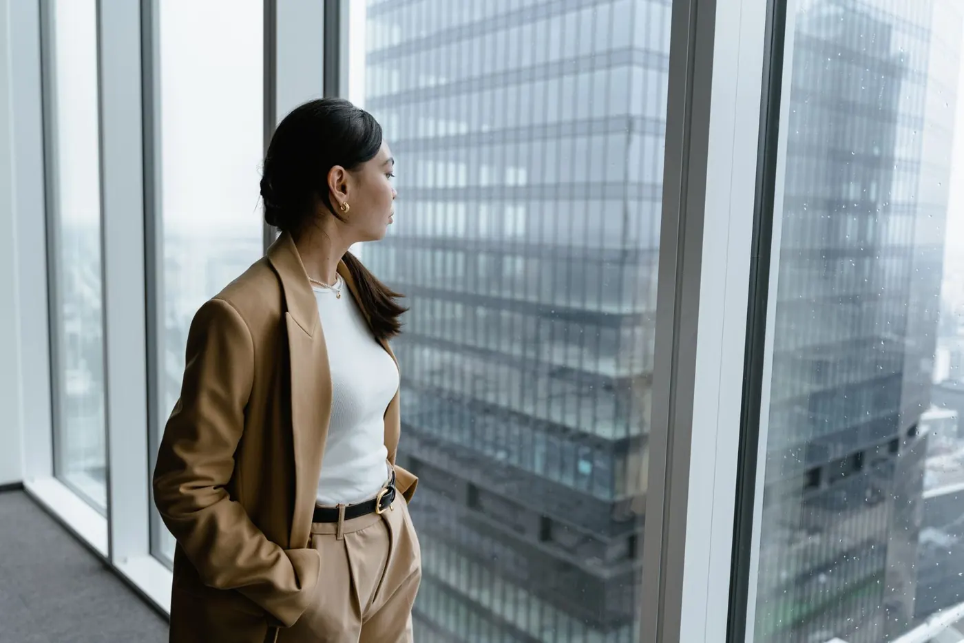 Femme réfléchissant à son évolution professionnelle près d'une fenêtre